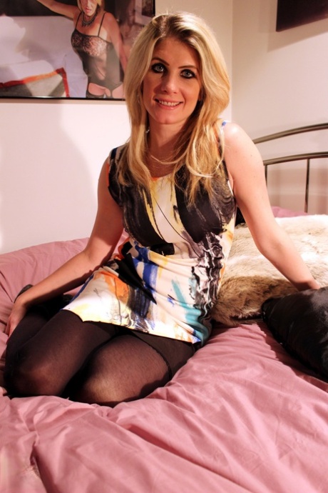 British woman with dirty blonde hair rolls off her stockings on top her bed 94137300