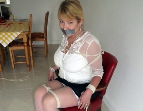 Blonde woman is silenced with duct tape while her tits are bound with rope