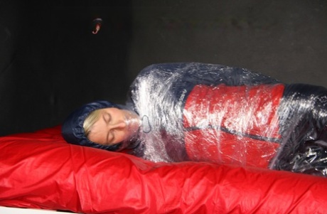 White girl is wrapped up with plastic wrap in nylon rain wear while barefoot 60016660