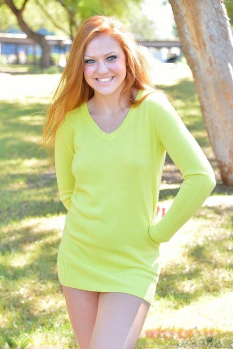 Young redhead spreads her legs while doing a naked handstand in a park